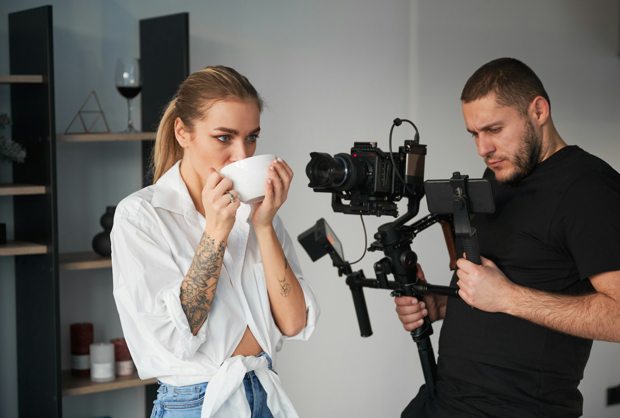 Videographer man shooting footage with female model, using camera.